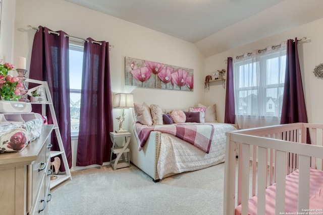 carpeted bedroom featuring a crib and lofted ceiling