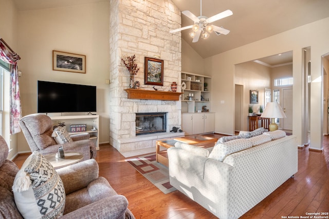 living room featuring wood-type flooring, high vaulted ceiling, built in features, ceiling fan, and a fireplace