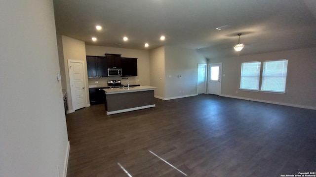 kitchen featuring dark wood-type flooring, appliances with stainless steel finishes, sink, and an island with sink