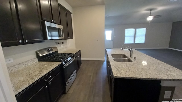 kitchen with an island with sink, sink, dark hardwood / wood-style flooring, light stone counters, and stainless steel appliances