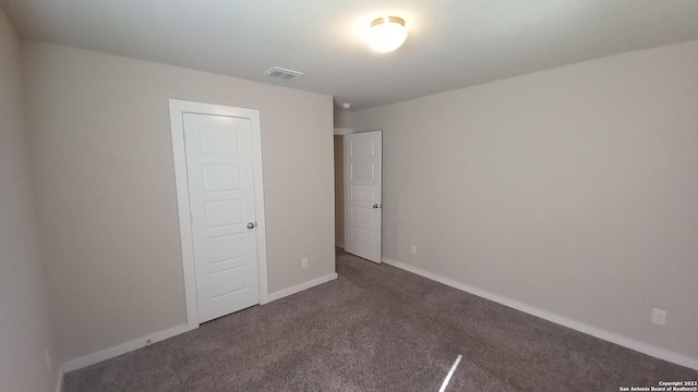 unfurnished bedroom featuring dark colored carpet and a closet