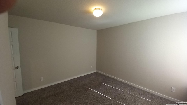 spare room featuring dark colored carpet