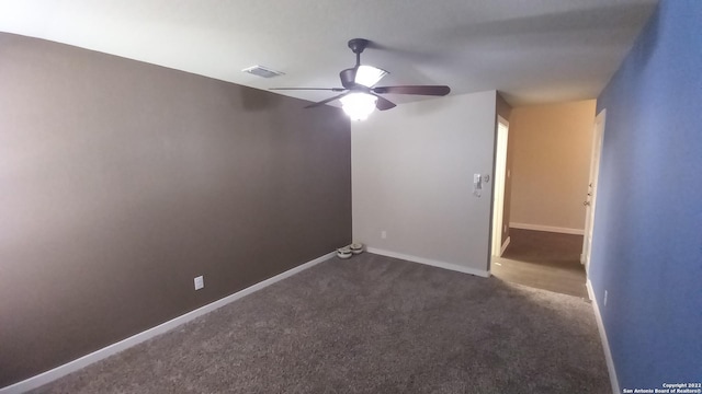 spare room featuring ceiling fan and dark carpet