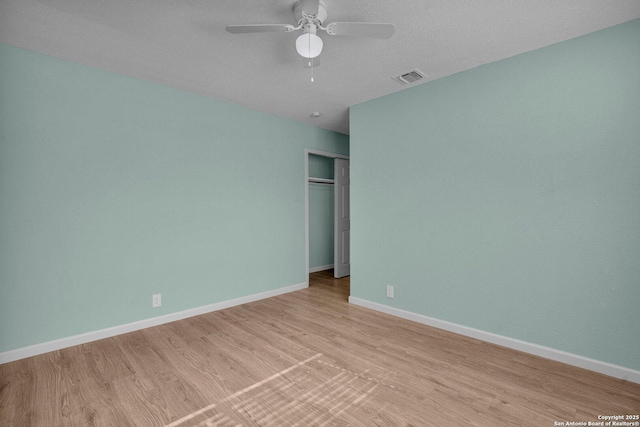 unfurnished bedroom with light wood-type flooring, a textured ceiling, ceiling fan, and a closet