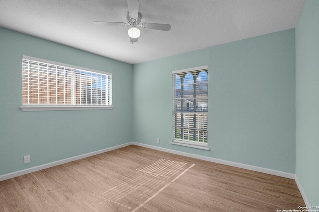 empty room with ceiling fan, a wealth of natural light, and light hardwood / wood-style floors