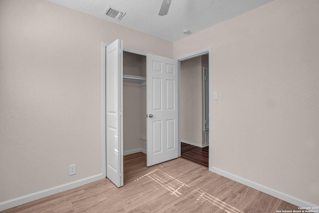 unfurnished bedroom featuring a closet, a textured ceiling, ceiling fan, and light hardwood / wood-style floors