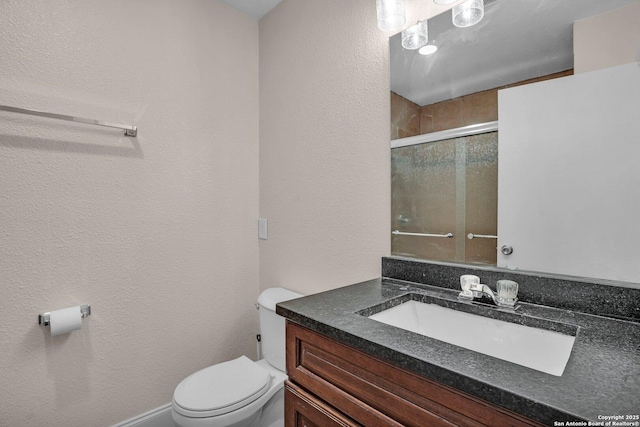 bathroom with vanity, a shower with shower door, and toilet