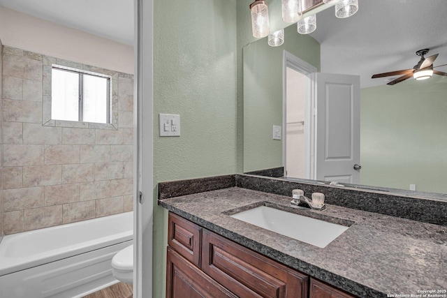 full bathroom featuring vanity, tiled shower / bath, ceiling fan, and toilet