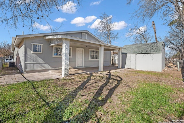 rear view of property with a storage shed, a yard, and central air condition unit