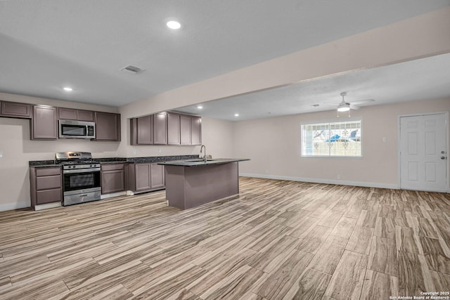 kitchen featuring sink, a center island with sink, a textured ceiling, ceiling fan, and stainless steel appliances