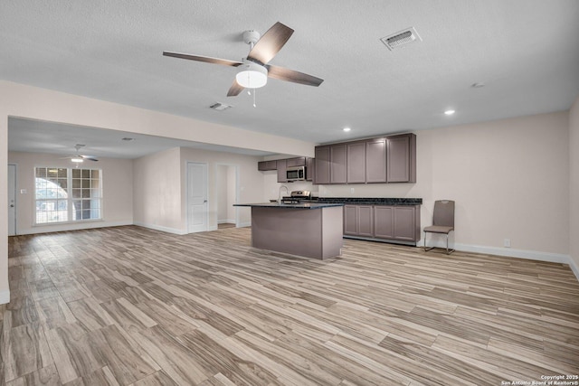 kitchen featuring sink, ceiling fan, appliances with stainless steel finishes, a kitchen island with sink, and light hardwood / wood-style floors