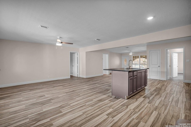 kitchen featuring sink, a kitchen island with sink, dark brown cabinetry, and light hardwood / wood-style floors