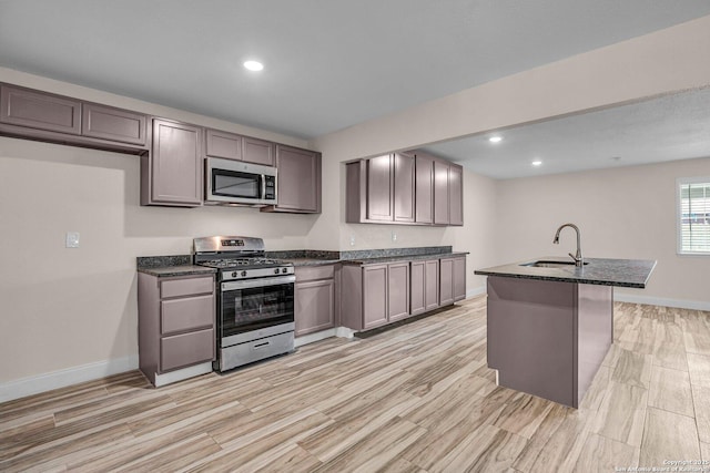 kitchen with sink, gray cabinets, stainless steel appliances, and a center island with sink