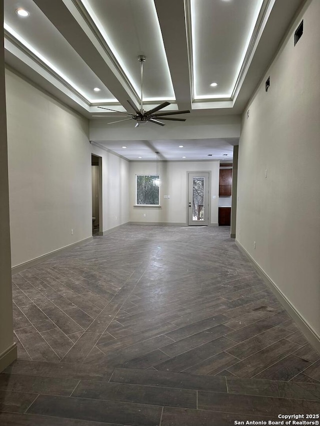 unfurnished living room with a raised ceiling, dark hardwood / wood-style flooring, and ceiling fan