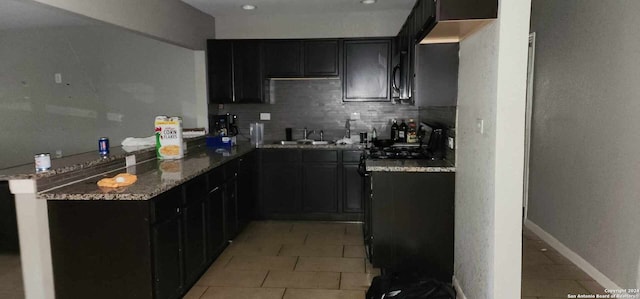 kitchen with sink, stone countertops, light tile patterned floors, kitchen peninsula, and decorative backsplash