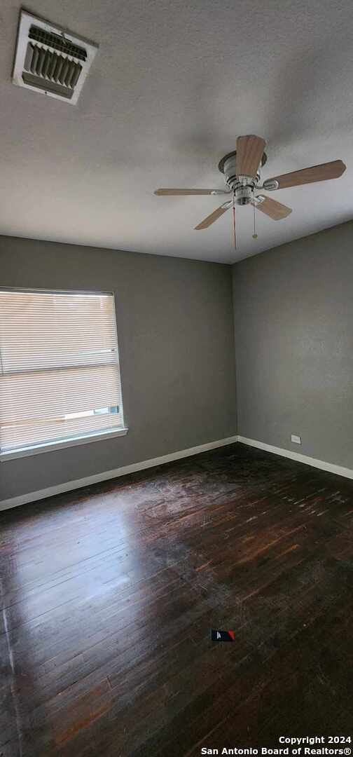 unfurnished room with dark wood-type flooring and ceiling fan