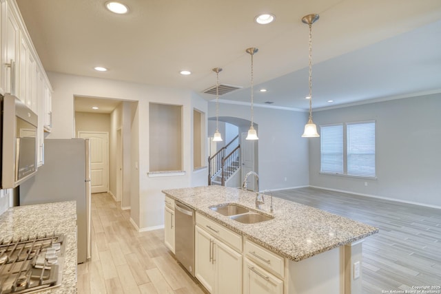 kitchen with sink, decorative light fixtures, stainless steel dishwasher, light stone countertops, and a kitchen island with sink