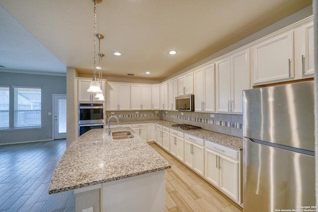 kitchen with light stone counters, white cabinetry, appliances with stainless steel finishes, and sink