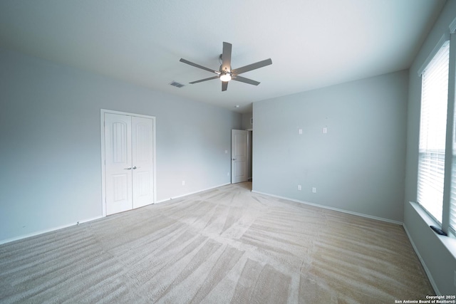 empty room with light carpet, ceiling fan, and a healthy amount of sunlight