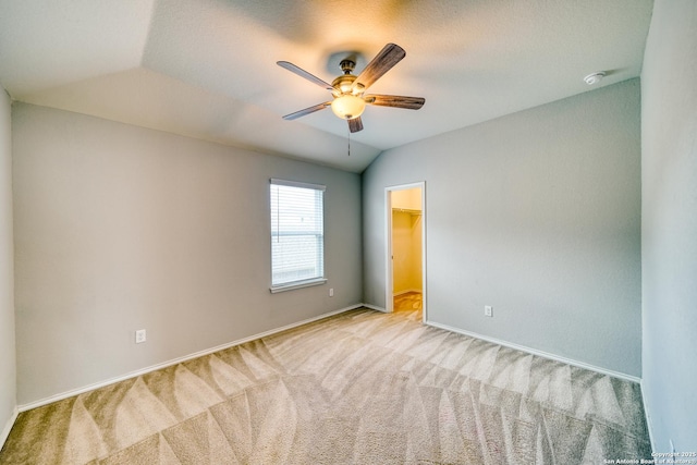 spare room featuring vaulted ceiling, light colored carpet, and ceiling fan