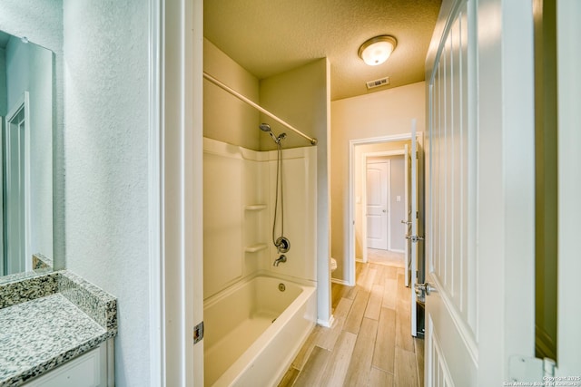 full bathroom featuring toilet, a textured ceiling, shower / washtub combination, vanity, and hardwood / wood-style flooring