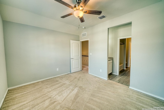 unfurnished bedroom with ensuite bathroom, vaulted ceiling, light carpet, and ceiling fan