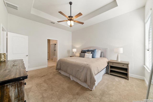 carpeted bedroom with ceiling fan, connected bathroom, and a tray ceiling