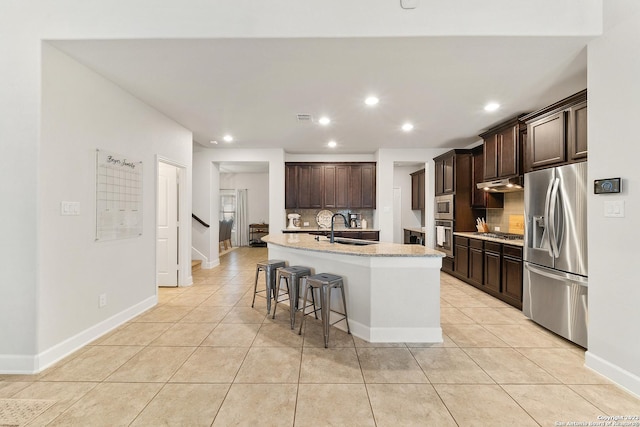 kitchen with sink, light tile patterned floors, a kitchen island with sink, stainless steel appliances, and decorative backsplash