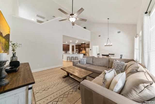 living room featuring ceiling fan with notable chandelier and high vaulted ceiling