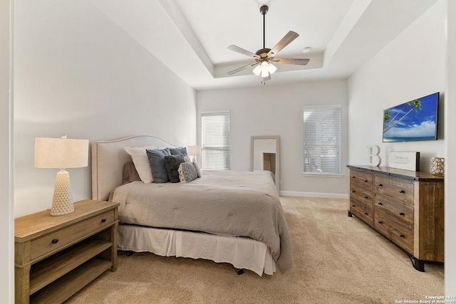 bedroom with ceiling fan, a raised ceiling, and light colored carpet