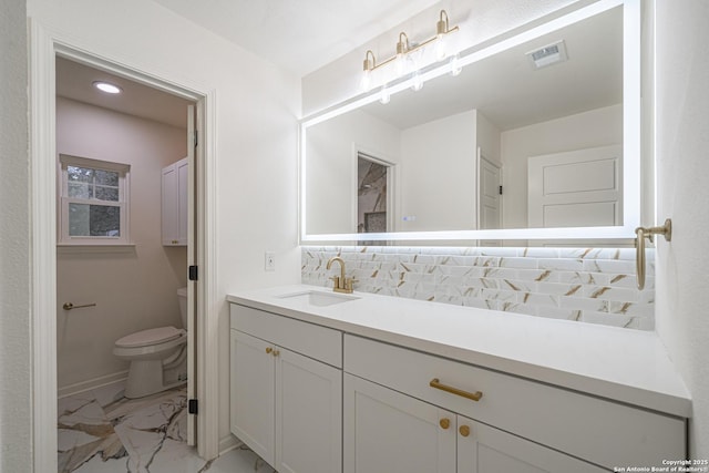 bathroom with vanity, toilet, and backsplash