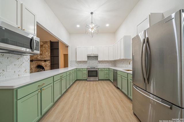 kitchen featuring pendant lighting, sink, green cabinets, white cabinetry, and appliances with stainless steel finishes