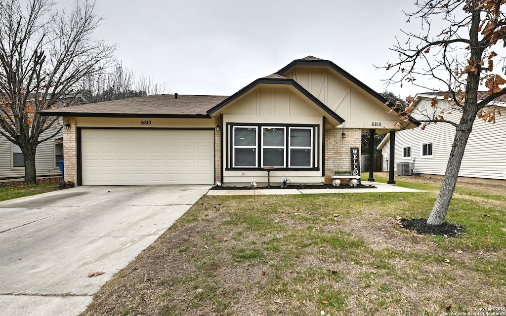 view of front of property featuring a garage, central AC unit, and a front yard