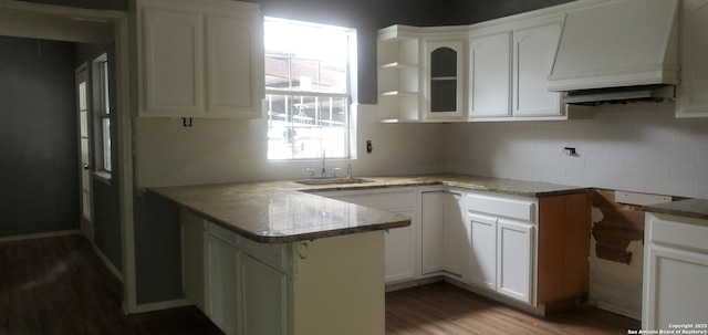 kitchen with sink, white cabinetry, hardwood / wood-style floors, custom exhaust hood, and kitchen peninsula