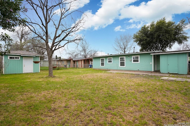 back of house with a lawn and a storage unit