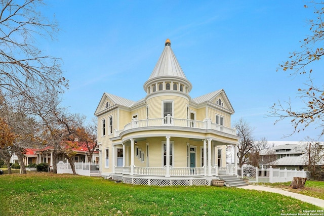 view of front facade featuring a porch, metal roof, fence, a balcony, and a front lawn