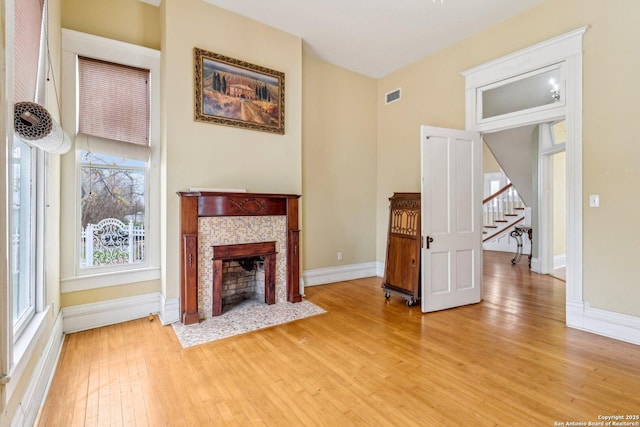 unfurnished living room featuring light wood finished floors, a fireplace, visible vents, and baseboards