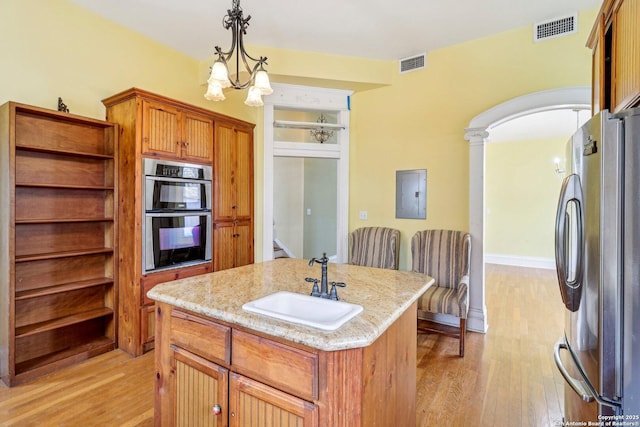 kitchen featuring visible vents, multiple ovens, freestanding refrigerator, and electric panel