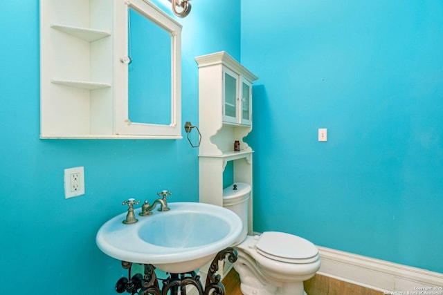 bathroom with wood finished floors, a sink, toilet, and baseboards