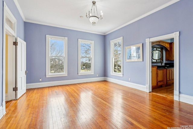 interior space featuring ornamental molding, a notable chandelier, light wood-style flooring, and baseboards