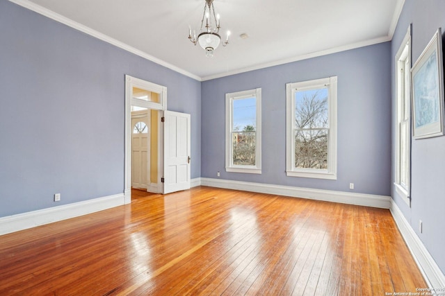 unfurnished room featuring baseboards, crown molding, hardwood / wood-style flooring, and a notable chandelier