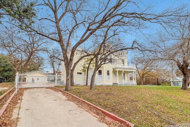 view of front of property with a chimney, covered porch, a gate, driveway, and a front lawn