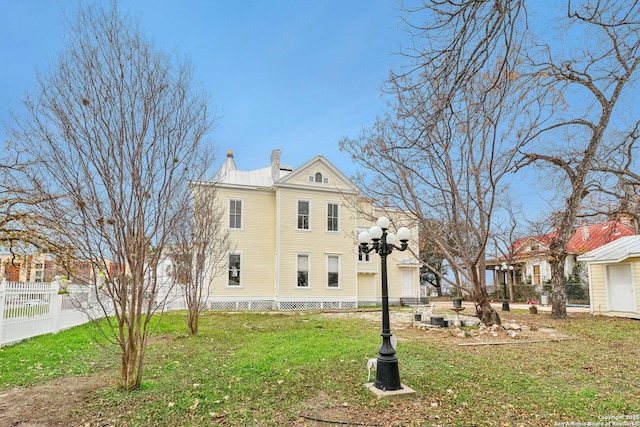 view of front of home with a front yard, fence, and a chimney