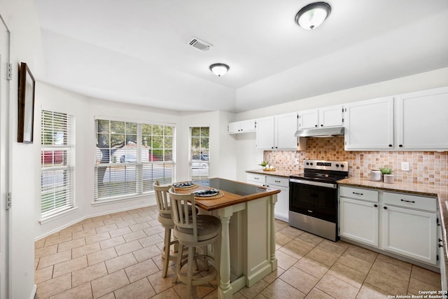 kitchen with electric stove, light tile patterned floors, white cabinetry, a kitchen breakfast bar, and decorative backsplash