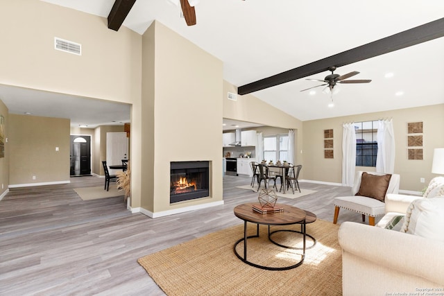 living room with hardwood / wood-style floors, a fireplace, lofted ceiling with beams, and ceiling fan