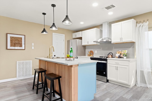 kitchen with white cabinets, white fridge, a kitchen island with sink, electric range, and wall chimney range hood