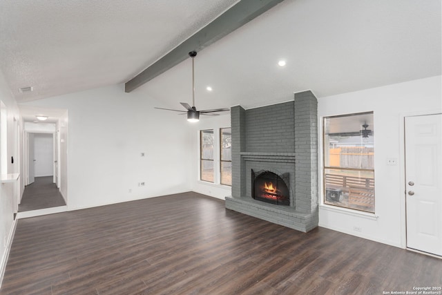 unfurnished living room featuring a brick fireplace, dark wood-type flooring, lofted ceiling with beams, and a healthy amount of sunlight