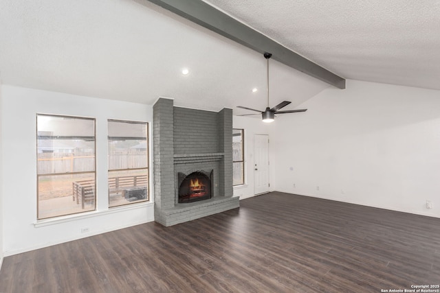 unfurnished living room with vaulted ceiling with beams, ceiling fan, a brick fireplace, dark wood-type flooring, and a textured ceiling