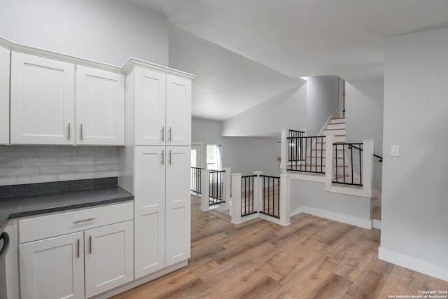 kitchen featuring tasteful backsplash, lofted ceiling, white cabinets, and light wood-type flooring