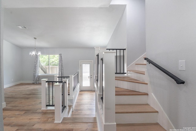 stairs featuring an inviting chandelier and hardwood / wood-style floors